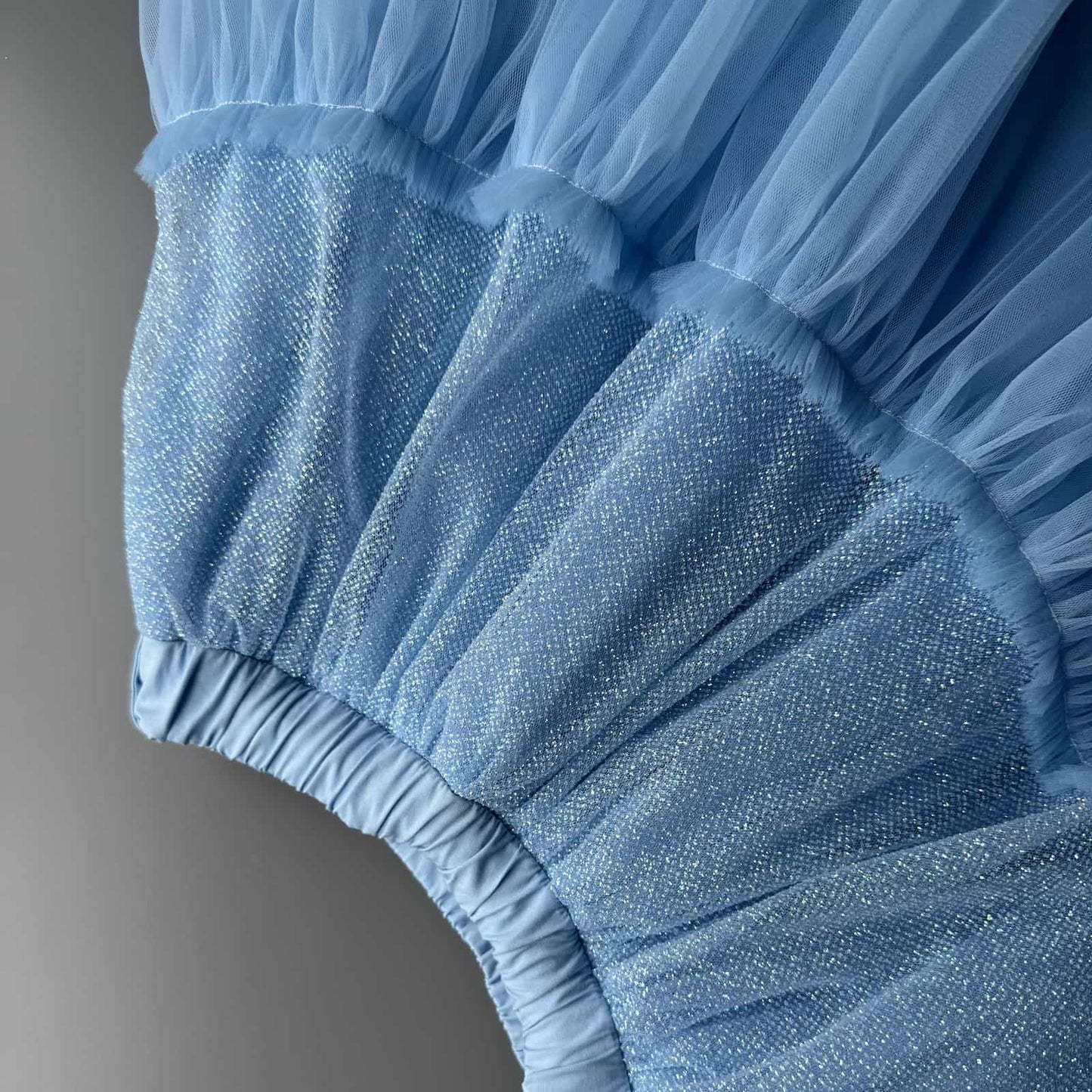 Close-up detail of blue glitter tulle skirt fabric for girls with soft sparkling layers and tulle texture