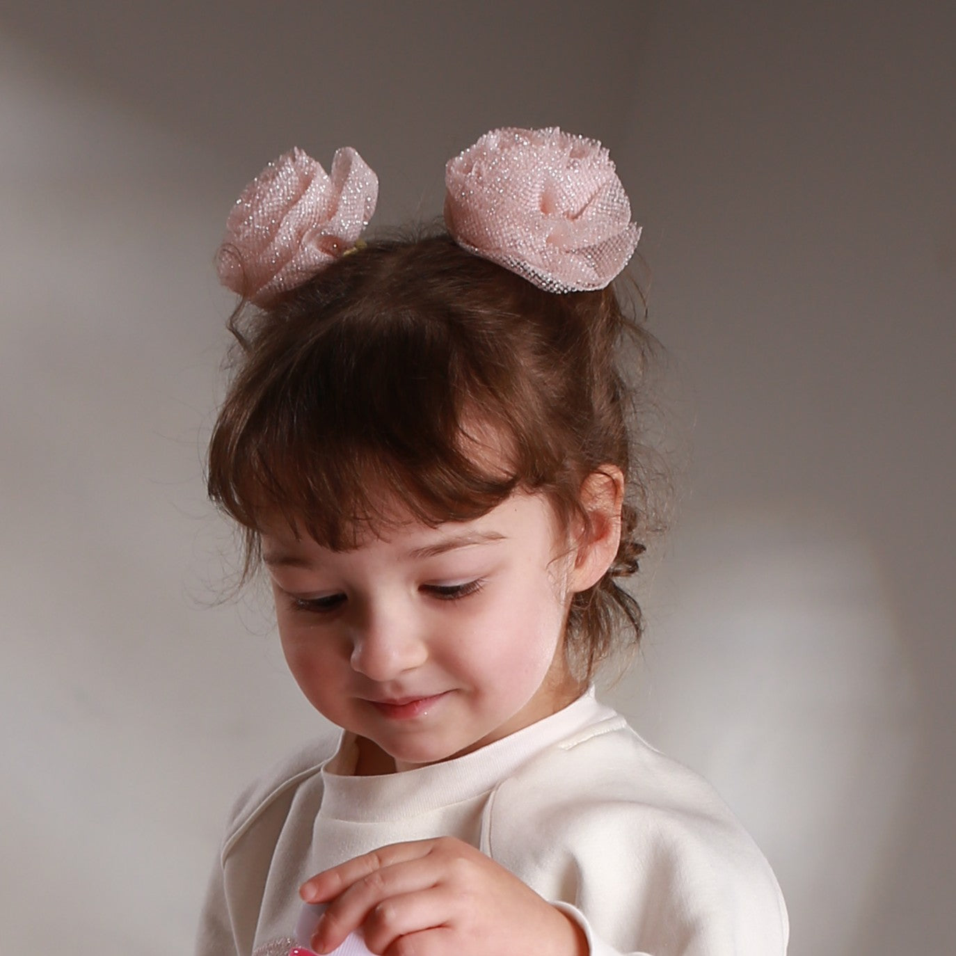 Girl wearing blush pink glitter tulle hair flowers – handmade elastic hair accessories for girls