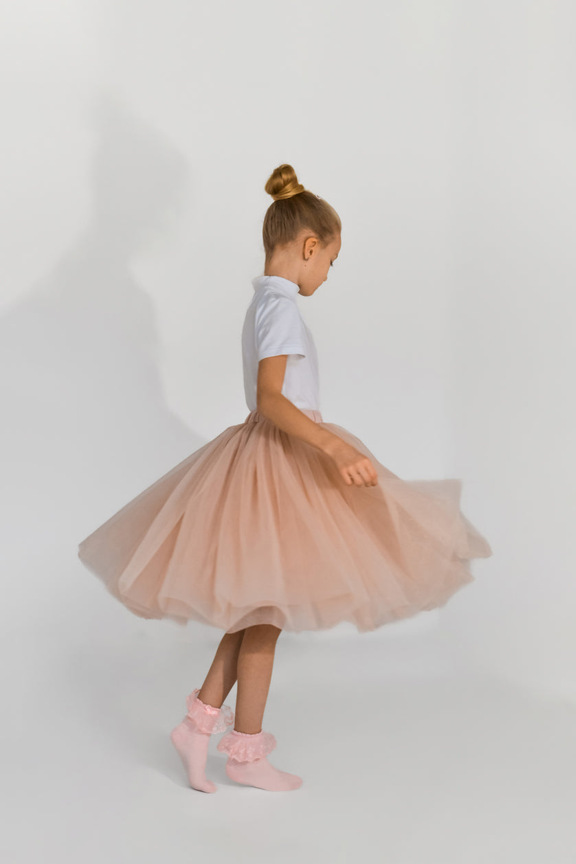 Girl twirling in blush pink tulle skirt – showing soft volume and flow