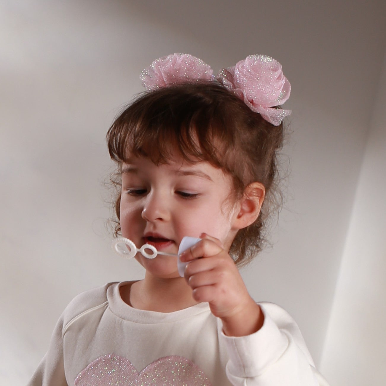 Girl wearing pink glitter tulle hair flowers – handmade festive hair accessories for toddlers and girls