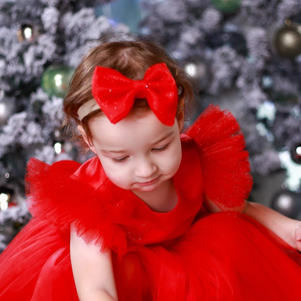 Girl wearing red glitter tulle hair bow – handmade festive hair accessory for babies and toddlers