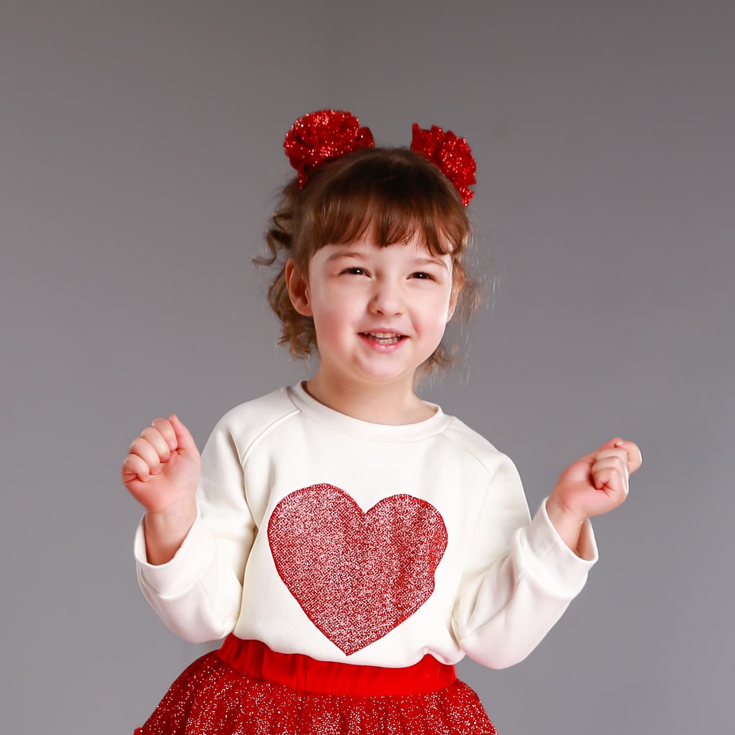 Close-up of girl wearing red glitter tulle hair flowers with heart sweatshirt – handmade festive hair accessories for girls
