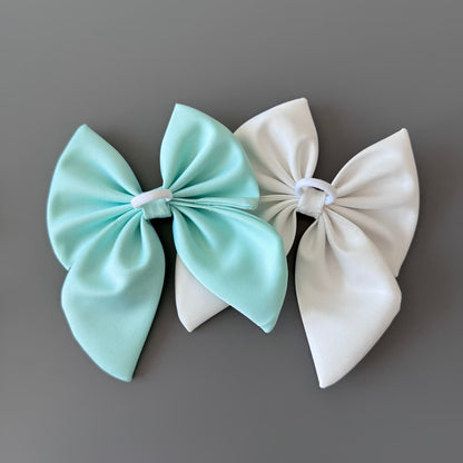 Back view of handmade satin hair bows in off white and mint with hand sewn elastic hair ties