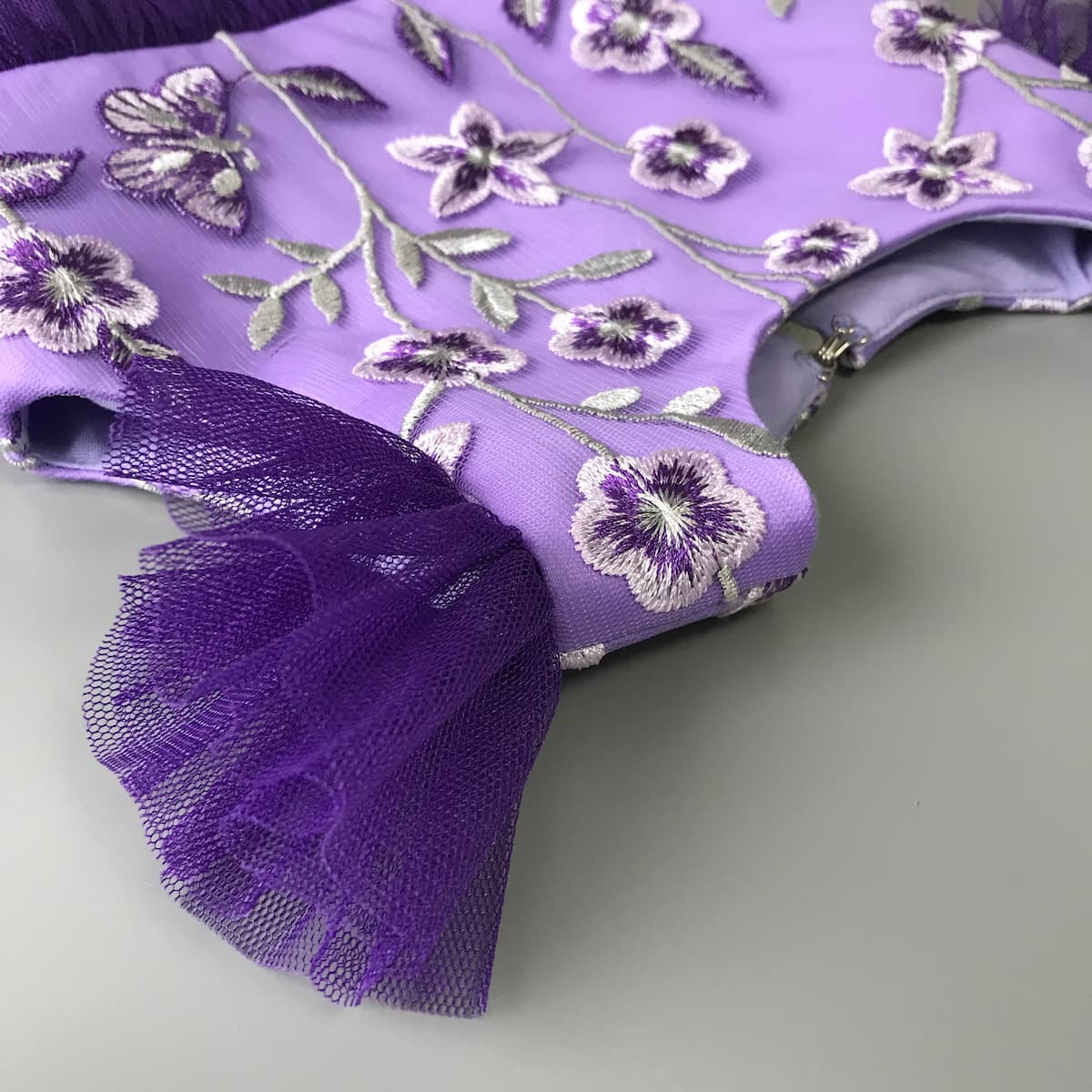 Detail von floraler Spitze und Tüllärmeln in Lila, festliches Kleid für Mädchen mit hochwertigen Materialien