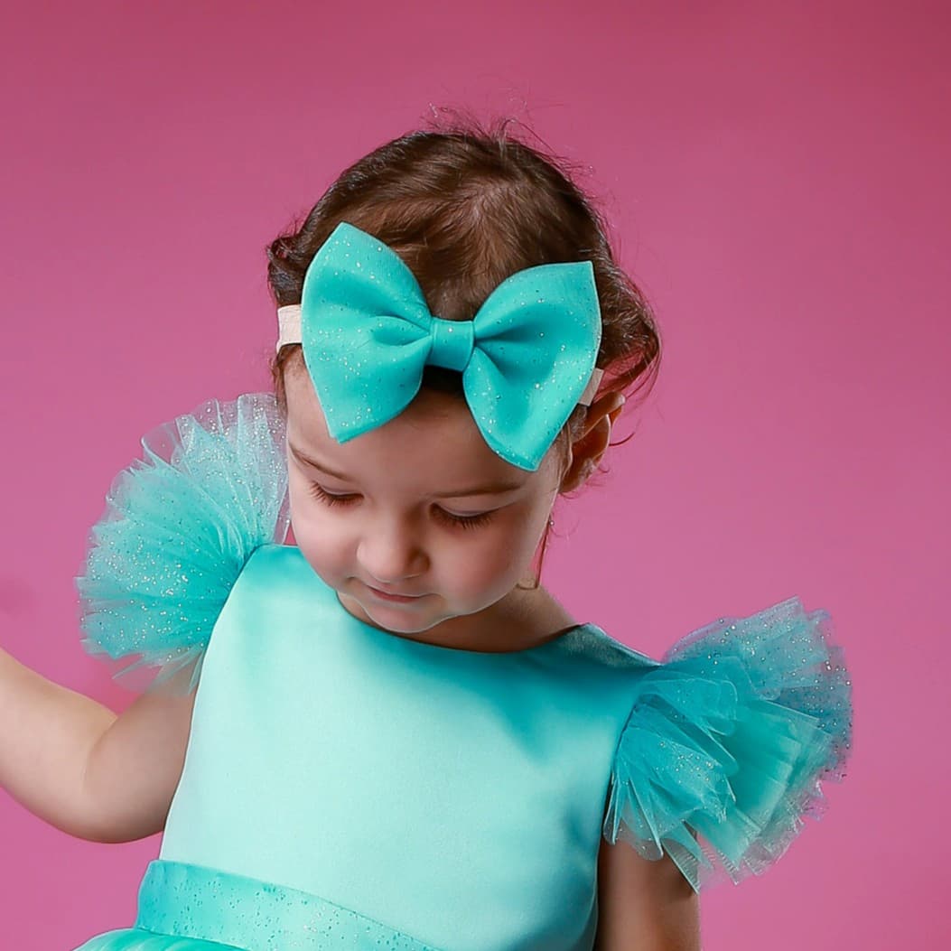 Girl wearing turquoise glitter tulle hair bow – handmade festive hair accessory for babies and toddlers