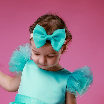 Girl wearing turquoise glitter tulle hair bow – handmade festive hair accessory for babies and toddlers